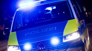 Ein Polizei-Einsatzfahrzeug steht mit eingeschaltetem Blaulicht an einer Einsatzstelle.