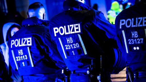 Polizisten in schwarzen AnEinsatzanzügen stehen im dunkeln nebeneinander