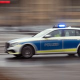 Ein Polizeiwagen fährt mit Blaulicht auf einer Straße.