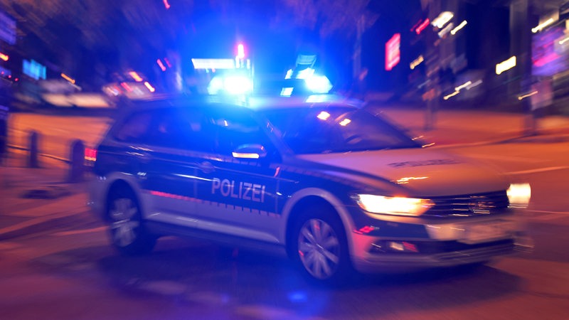 Ein Polizeiauto fährt mit Blaulicht im Dunkeln durch die Stadt.