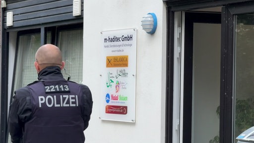 Ein Polizist steht vor den Geschäftsräumen der islamischen Zielgruppe in Huchtingen. 