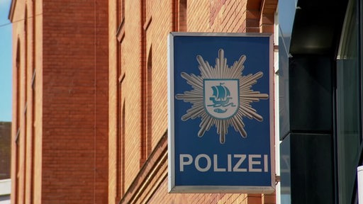 Ein Polizeischild an einer Backsteinfassade.