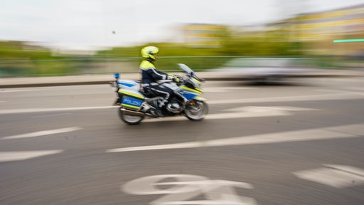 Ein Polizist fährt mit seinem Motorrad durch die Innenstadt.