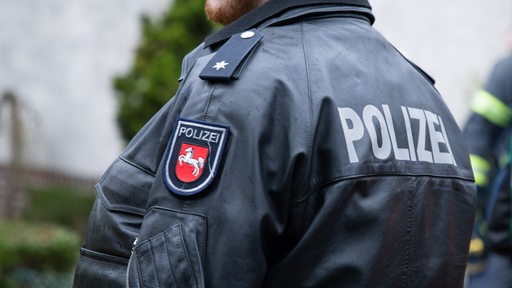 Ein Beamter der Polizei Niedersachsen mit Schriftzug und dem Landeswappen auf der Polizeijacke.