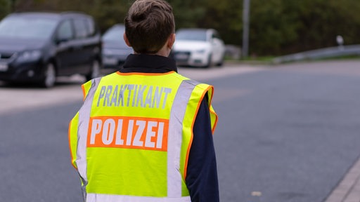 Ein Praktikant der Polizei trägt eine Warnweste.