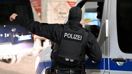 Polizisten stehen im Rahmen einer groß angelegten Razzia vor einem Haus. 