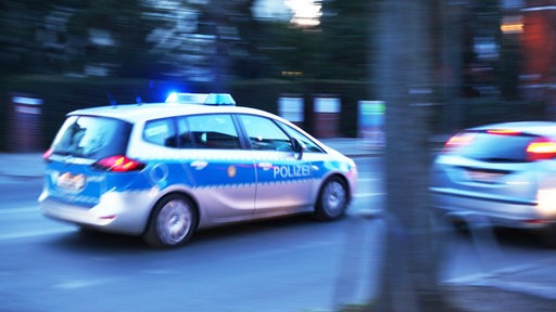 Ein Polizeiauto fährt mit Blaulicht über eine Straße