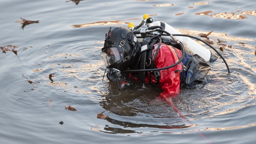 Ein Polizeitaucher sucht in einem See nach Beweismitteln. 