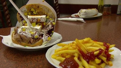 Teller mit Döner und Pommes stehen auf einem Esstisch.