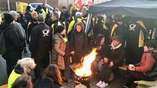 Post-Beschäftigte sitzen an Feuerstelle in Bremen