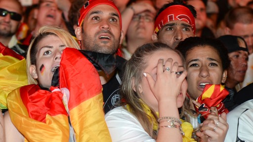 Zahlreiche Fans mit Fahnen haben entsetzte Gesichtsausdrücke.