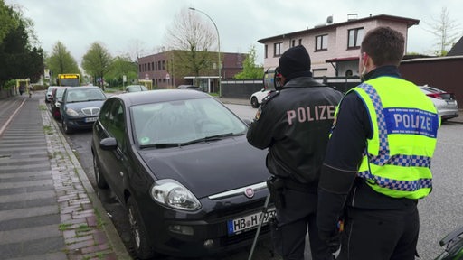 Zwei Polizisten stehen im Rahmen einer Radarkontrolle an einer Straße.