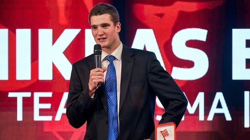 Radsportler Niklas Behrens steht bei der Sportgala auf der Bühne und spricht in ein Mikrofon.