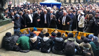 Bremens Bürgermeister Andreas Bovenschulte und Bundeswirtschaftsminister Peter Altmaier stehen vor Demonstranten, die ihnen den Zugang zum Bremer Rathaus blockieren.