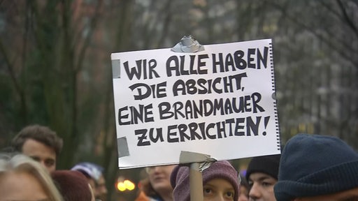 Eine Person hält ein Schild hoch.