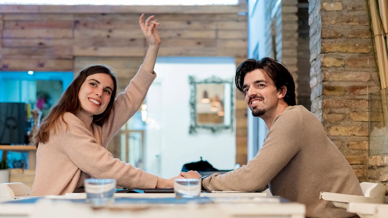 Eine Frau ruft in einem Restaurant nach dem Kellner.