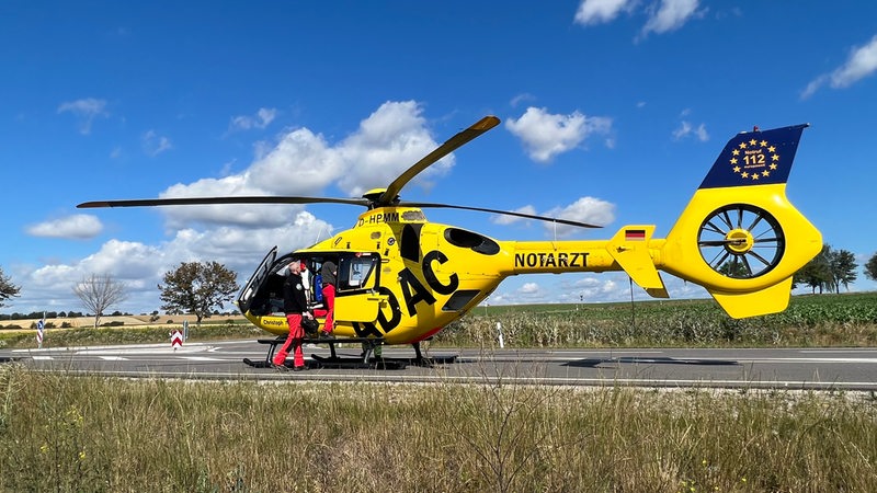 Ein Rettungshubschrauber steht auf einer Landstraße.