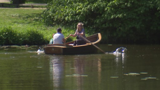 Eine Familie fährt in einem Ruderboot über einen See.