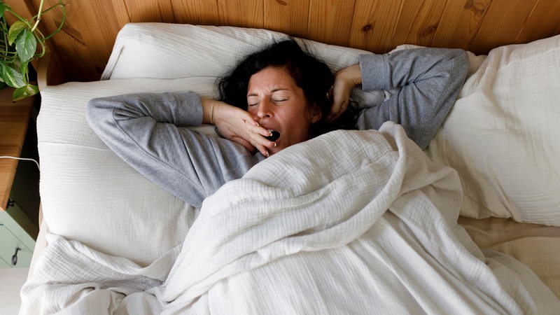 Eine Frau liegt gähnend in ihrem Bett