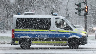 Ein Polizeiwagen fährt auf einer Straße im Schnee.