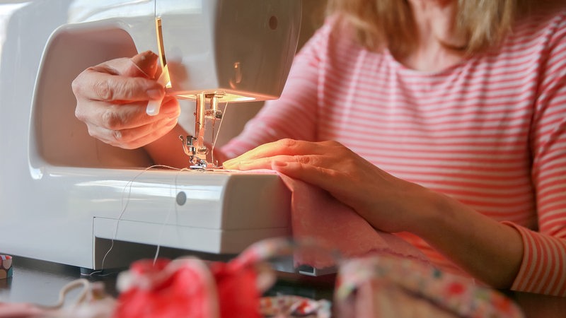 Eine Frau arbeitet an einer Nähmaschine (gestellte Szene)