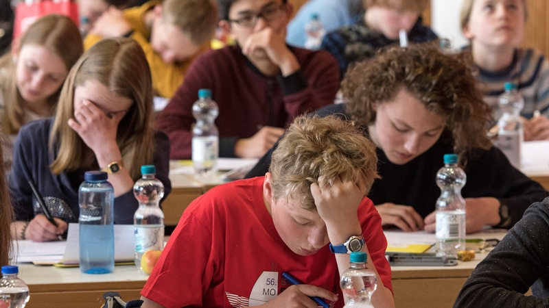 Schüler sitzen in einem Raum und schreiben 