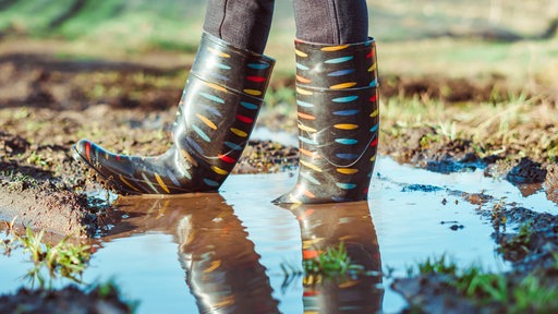 Bunte Gummistiefel in einer Pfütze.