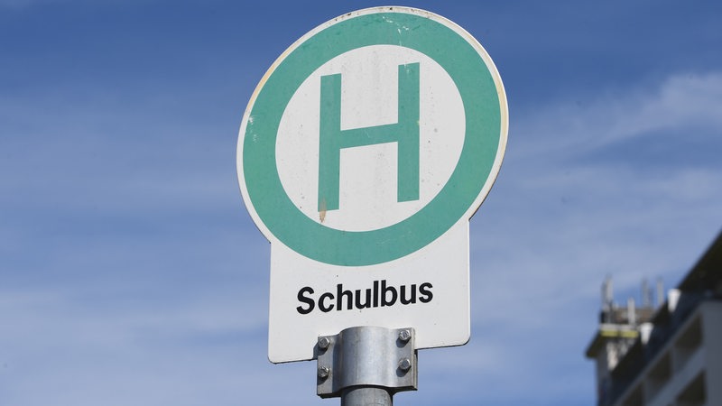 Vor einem blauen Himmel steht ein verblichenes Schulbus-Schild.