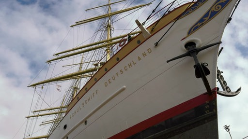 Ein großes, altes Segelschiff, auf dem "Schulschiff Deutschland" steht, liegt trocken in der Bredo-Werft.