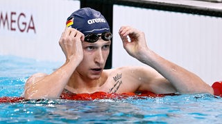 Florian Wellbrock hebt im Becken die Schwimmbrille hoch.