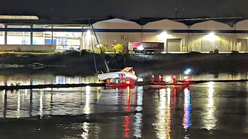 Ein gekentertes Segelboot nachts am Weser-Ufer