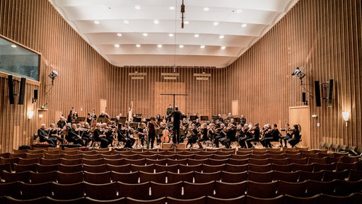 Musiker eines Symphonie-Orchesters stehen auf der Bühne des Sendesaals in Bremen