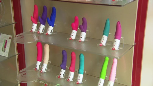 Im Regal eines Sexshops stehen viele bunte Dildos und Dibratoren.