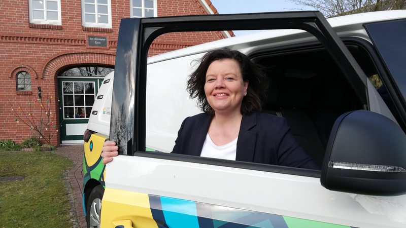 Eine Frau blickt durch das Fenster einer geöffneten Autotür.