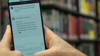 Ein Smartphone wird in den zwei Händen gehalten. Auf dem Handybildschirm ist das Programm Chat-GPT zu sehen.