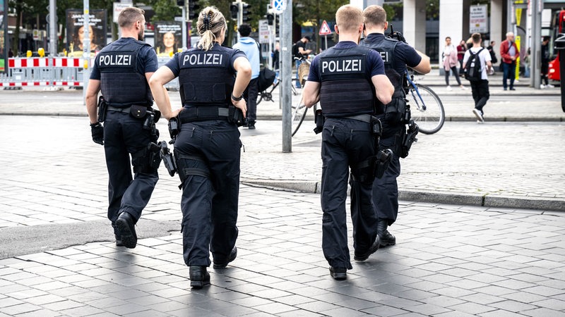 Einsatzkräfte der Polizei laufen über den Bahnhofsvorplatz.