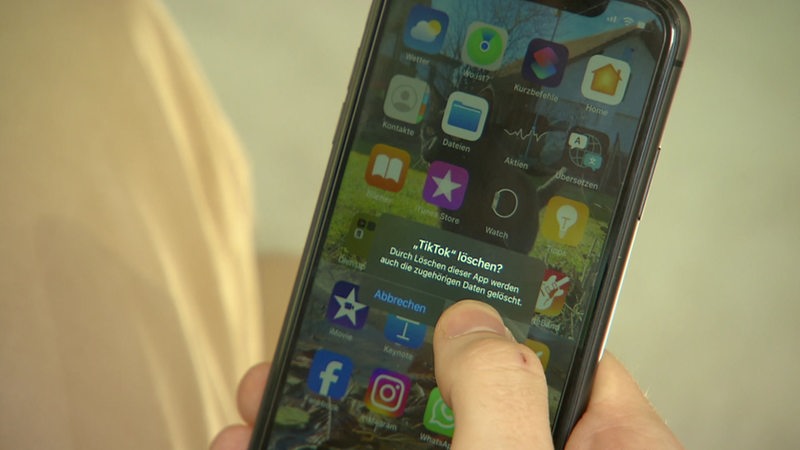 Eine Person löscht die App TikTok auf seinem Handy. 