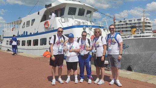 Einige Athleten und Athletinnen des US-Teams stehen in Bremerhaven vor einem Ausflugsdampfer.