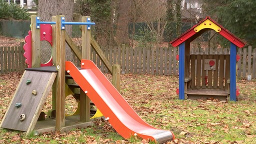 Zu sehen ist ein Spielplatz mit einer Rutsche und einem kleinen Spielhäuschen.