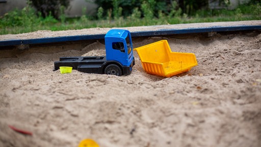 Ein Spielzeug liegt in einem Sandkasten.