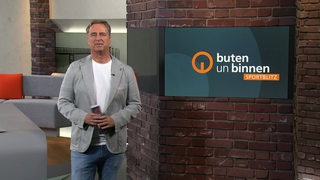 Der Moderator Stephan Schiffner steht im Sportblitz-Studio vor einer Wand.