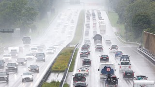 Auf einer Autobahn stehen Fahrzeuge in beiden Richtungen im Stau, es regnet