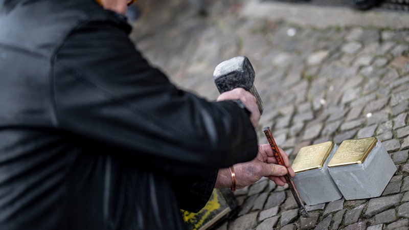 Eine Person bereitet bei der Verlegung der Stolpersteine für Ludwig M'Bebe Mpessa und Erika Emilie Mpessa in Berlin-Prenzlauer Berg den Pflaster vor. 