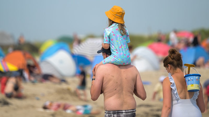 Eine Familie läuft an einem Nordsee-Strand entlang.