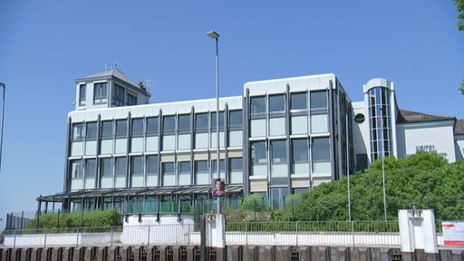 Es ist ein großes Bürogebäude an einem sonnigen Tag zu sehen.