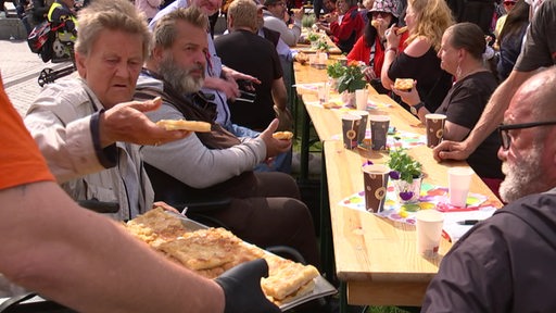 Menschen im freien an einer langen Holztafel mit Kaffee und Kuchen