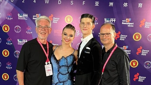 Gründ-Gold-Präsident Jens Steinmann, Helene Novalee Tilgert, Dmytrii Forostianov und Trainer Fred Jörgens posieren nebeneinander.