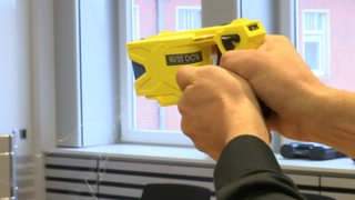 Ein Taser, der von zwei Händen gehalten wird.