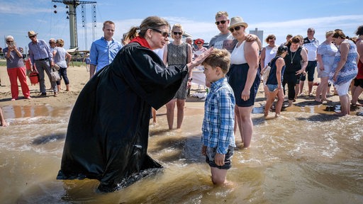 Ein Kind wird in der Weser getauft.