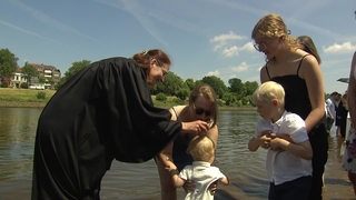 Ein Kind wird in der Weser getauft